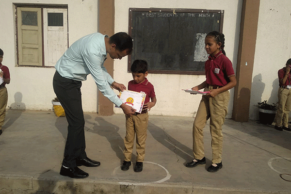 Mr. Deepak Dubey principal of RIS Mehsana giving certificate to student